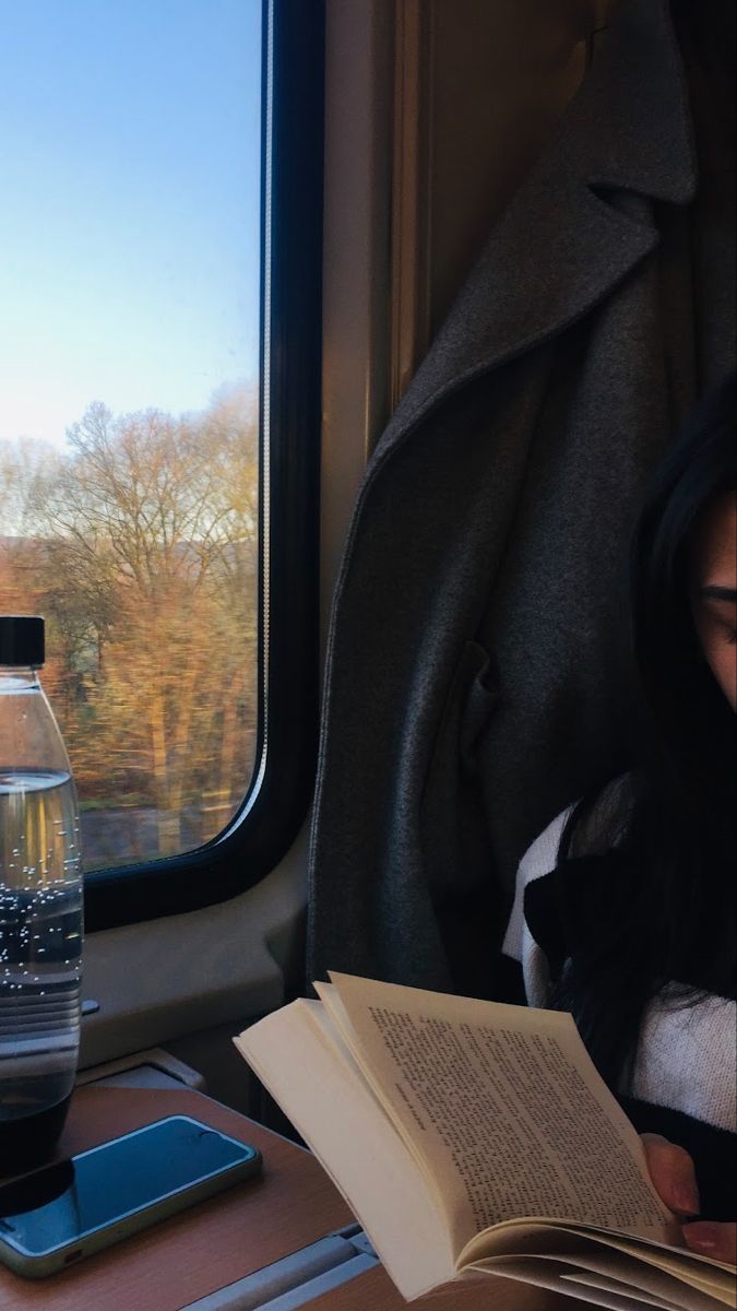 a woman sitting on a train reading a book