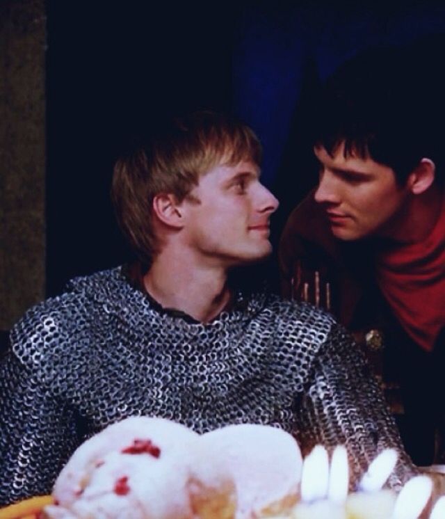 two men sitting next to each other with candles in front of them