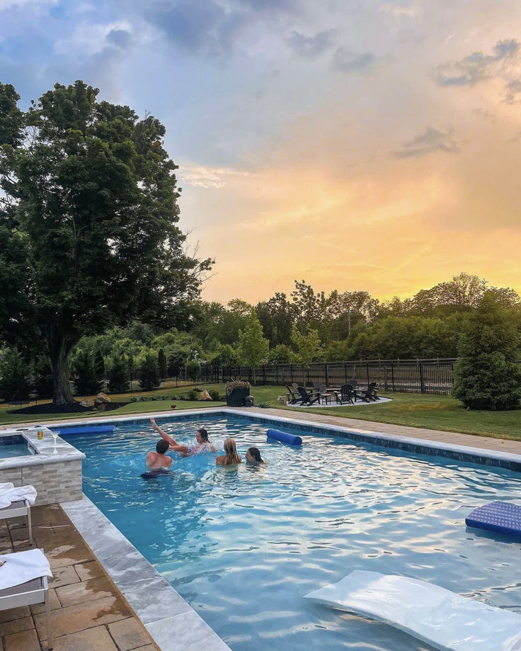 several people are in the pool at sunset