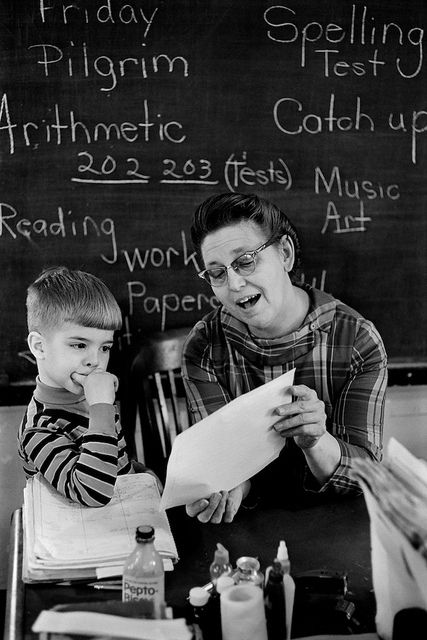 a man and boy sitting at a table in front of a blackboard with writing on it