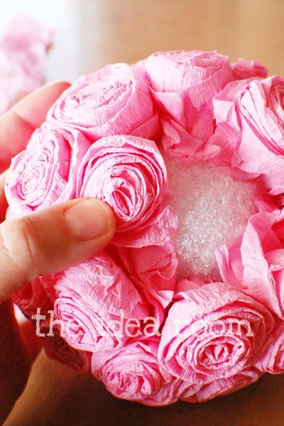 a person is holding a pink flower in their hand and it looks like they are made out of paper