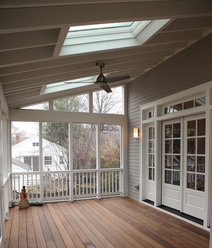 an empty porch with wood floors and white doors