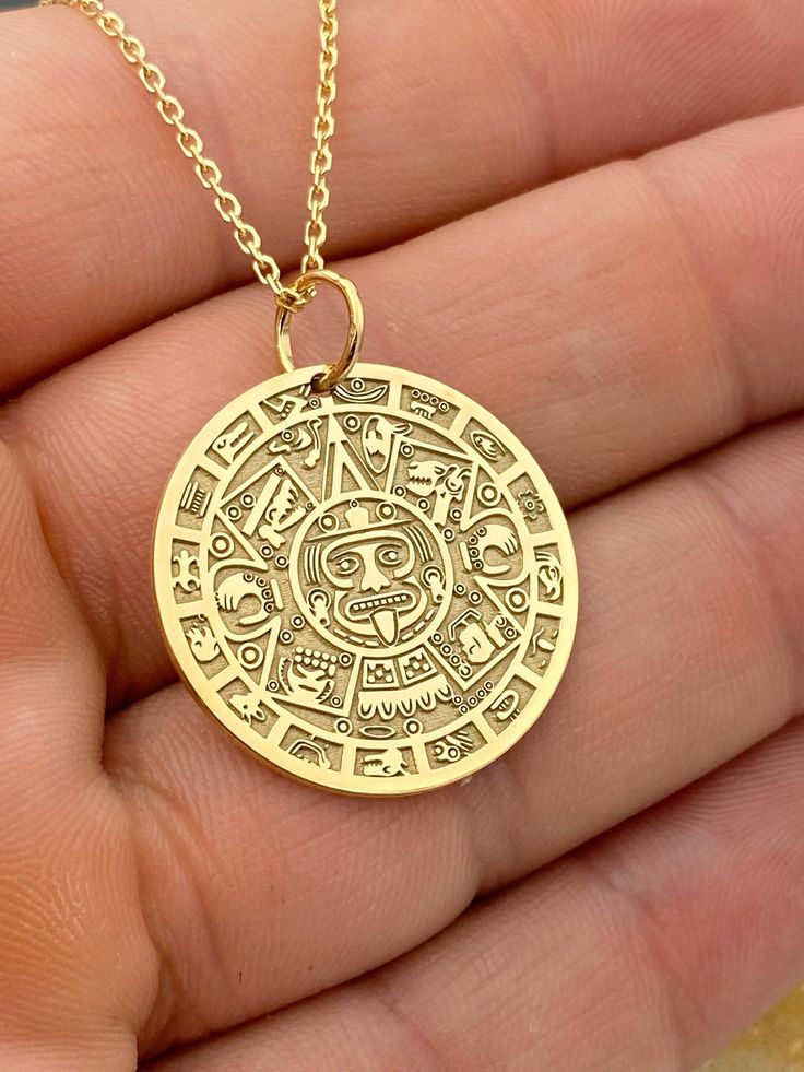 "14k Aztec Calendar Necklace, Personalized Mayan Sun Calendar Pendant, Aztec Coin Pendant, Sun Stone Aztec Calendar Necklace 14k Solid Gold Choose What Size You Want the Pendant Using The First Option Box Choose Chain Length Or Without Chain Using The Second Option Box Photos Are For The 25.4 mm / 1 Inch Diameter Pendant Pendant thickness : 0.7mm  Contact us if you want it thicker Inner diameter of jump ring : 5mm Contact us if you need it bigger  Chain width : 1.30mm     ♥  Material of pendant and chain: Solid Gold k14  ♥  Packaging: All of our jewelry are beautifully boxed and ready for gifting For more personalized designs take a look here: ♥ www.etsy.com/listing/736955132 ♥ www.etsy.com/listing/819494857 ♥ www.etsy.com/listing/823397880 ♥ www.etsy.com/listing/769847320 ♥ www.etsy.com/l Artisan Engraved Necklaces For Anniversary, Symbolic Handmade Coin Necklaces, Anniversary Amulet Style Jewelry With Coin Pendant, Anniversary Amulet Jewelry With Coin Pendant, Symbolic Engraved Brass Jewelry, Anniversary Jewelry With Coin Pendant Charm, Spiritual 14k Gold Coin Jewelry, Spiritual 14k Stamped Pendant Jewelry, Traditional Yellow Gold Personalized Jewelry