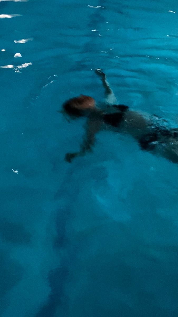 a man swimming in the blue water with his head above the water's surface