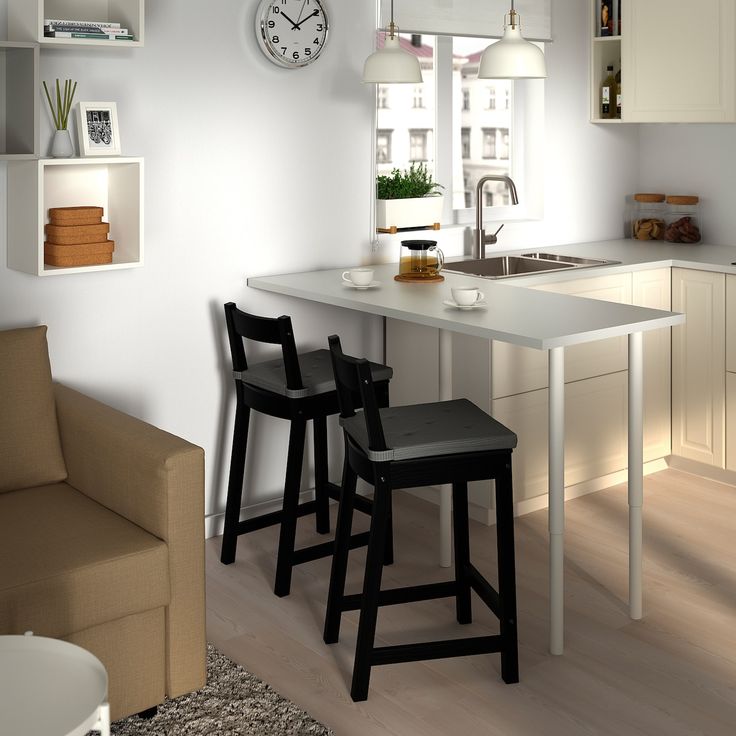 two stools sit in front of a kitchen counter with a clock on the wall