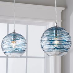 two glass globe lights hanging from a window sill in front of a white wall