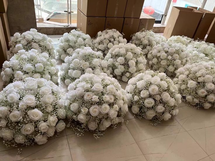 several bouquets of white roses are arranged on the floor