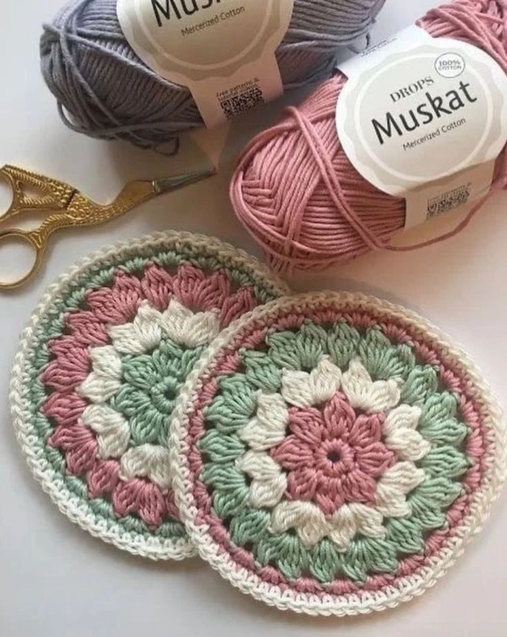 three crocheted coasters with yarn and scissors next to them on a table