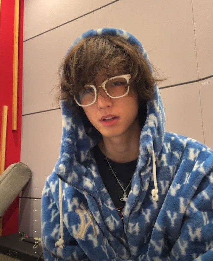 a young man wearing glasses and a blue hoodie