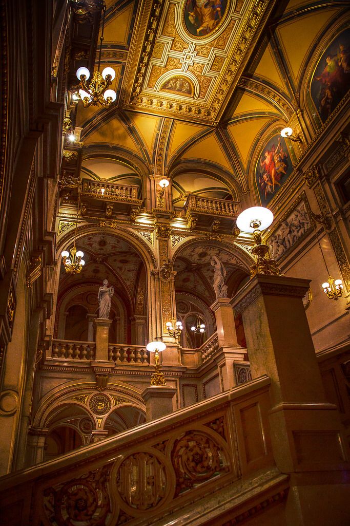 an ornate staircase with chandeliers and paintings on the ceiling