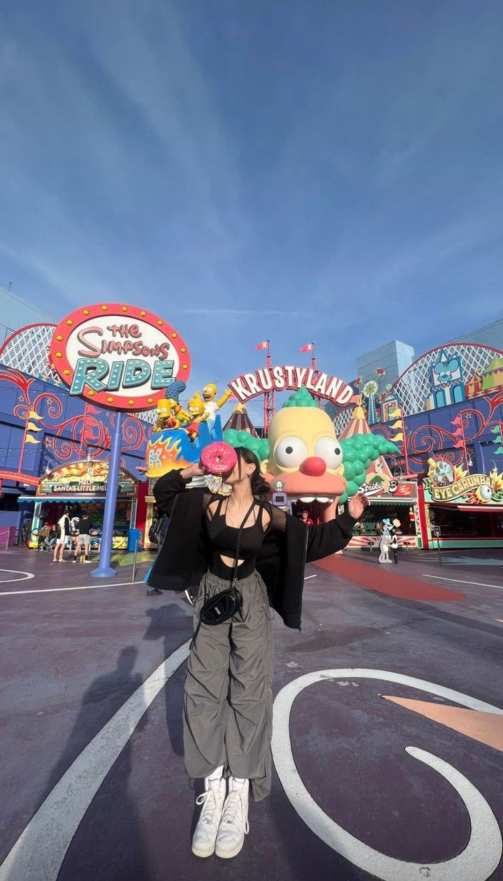 a woman standing in front of an amusement park with clowns on it's head