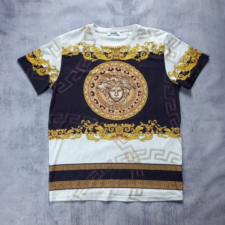 Versace Graphic Print Rapper Style T-Shirt Size: X-Large Great Condition. The Back Thread Has Started To Come Undone. Please See The Pictures. Chest 21" Back 28” Brand: Versace Fabric: 100% Cotton Country Of Origin: Italy Colour: White/Gold We Kindly Remind You That Vintage Items Typically Exhibit Natural Signs Of Wear Or Fading, Reflective Of Their Age. However, We Assure You That Any Noticeable Imperfections Such As Stains Or Holes Will Be Duly Mentioned. Please Be Aware That The Actual Colors Luxury Monogram Print Short Sleeve T-shirt, Luxury Short Sleeve T-shirt With Graphic Print, Luxury Graphic Print Tops For Streetwear, Luxury Monogram Print Crew Neck T-shirt, Luxury Gold Short Sleeve Tops, Luxury Monogram Print Streetwear Top, Luxury Monogram Print Top For Streetwear, White Fashion Print Tops For Streetwear, Luxury Gold Top With Graphic Print