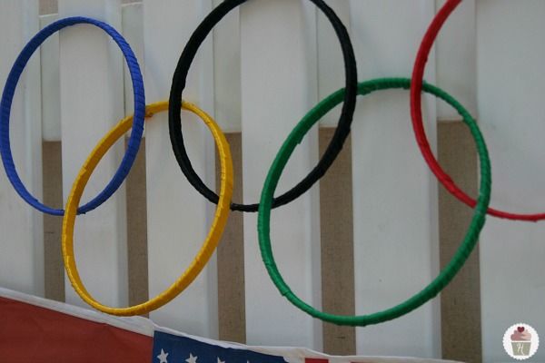 four olympic rings hanging from the side of a fence with an american flag in the background