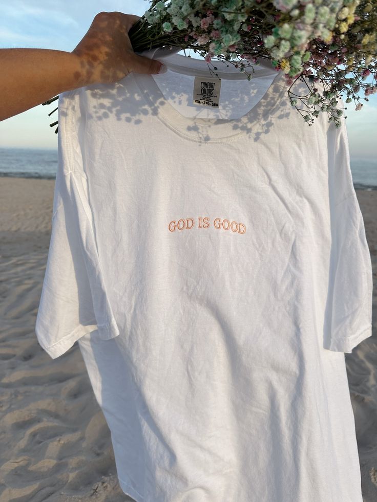 Introducing our Women's Boyfriend Tee, a perfect blend of dainty and trendy fashion with a faith-based touch. This relaxed-fit tee is designed for both comfort and style, crafted from soft, high-quality fabric. The front features a delicate, dainty embroidery of the phrase "God is Good," adding a subtle yet meaningful accent. Its versatile design makes it easy to pair with jeans, shorts, or skirts for a chic, casual look. Embrace your faith and style with this cute and trendy tee, a must-have ad Inspirational Relaxed Fit T-shirt For Spring, Inspirational Graphic Print T-shirt For Summer, Inspirational Short Sleeve T-shirt For Summer, Pink T-shirt With Embroidered Text For Summer, Inspirational White T-shirt For Everyday, Pink Embroidered T-shirt For Summer, Inspirational Pink Cotton T-shirt, Summer Everyday T-shirt With Embroidered Text, Inspirational Letter Print T-shirt For Spring