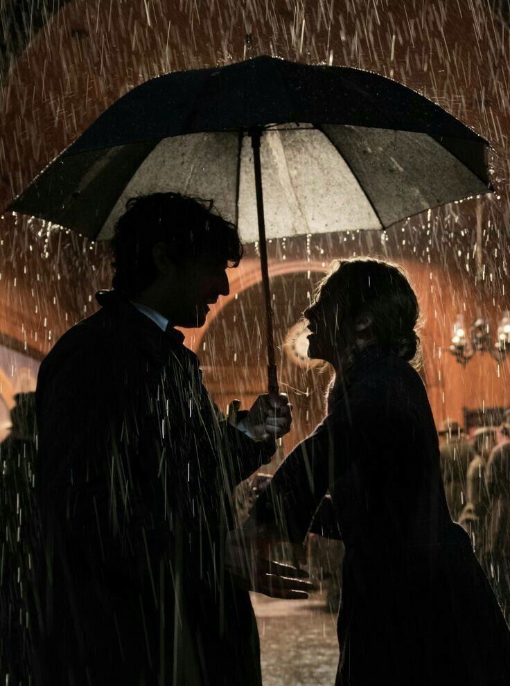 two people standing under an umbrella in the rain