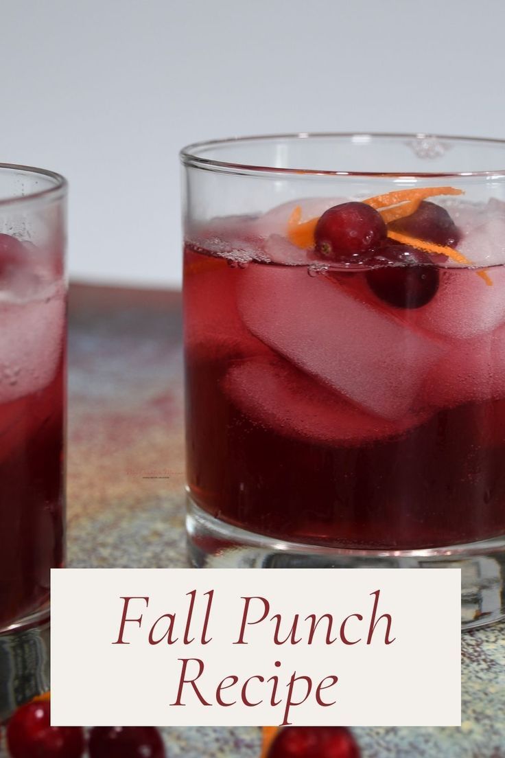 two glasses filled with red liquid and cherries next to each other on a table