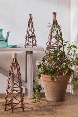 three small wooden trees sitting on top of a table next to a potted plant