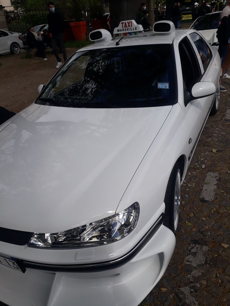 a white car parked on the side of a road next to other cars and people