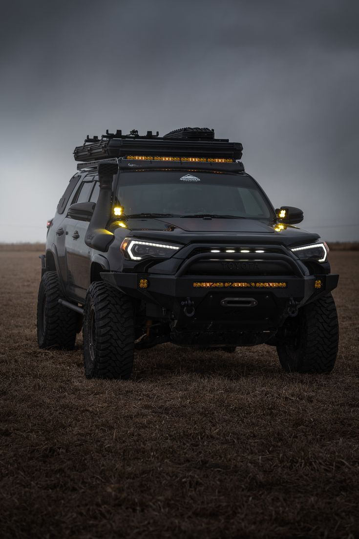 an off - road vehicle is parked in the middle of a field with lights on