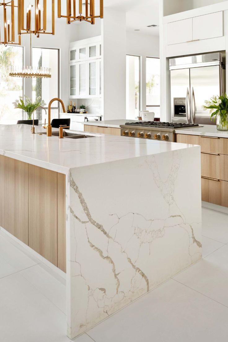 a large kitchen with marble counter tops and wooden cabinetry, along with an island in the middle