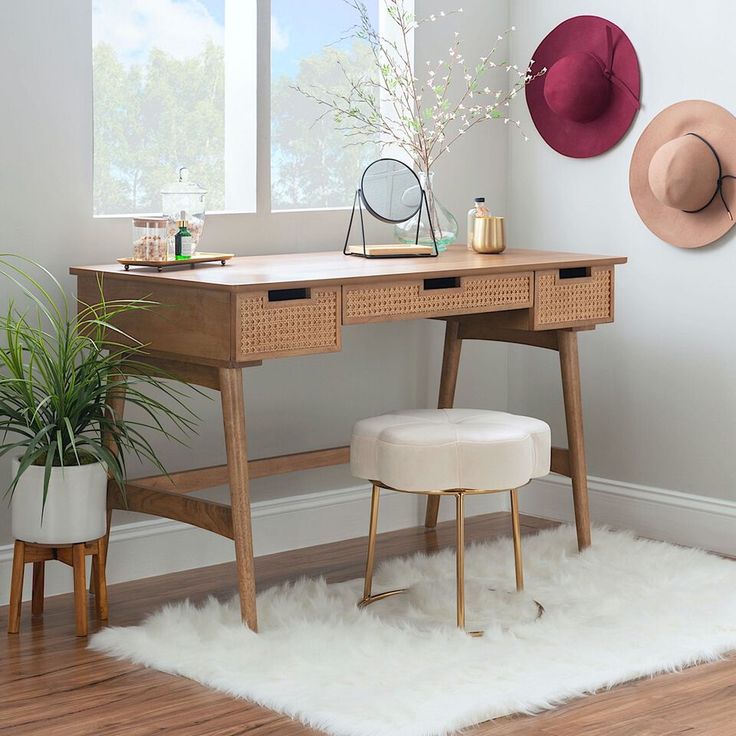 a desk with two hats hanging on the wall and a stool in front of it