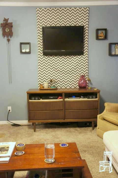 a living room with couches, coffee table and television mounted on the wall above it