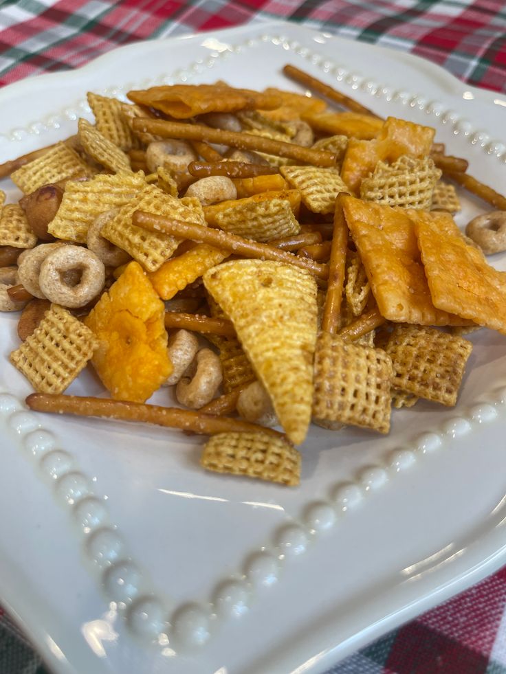 a white plate topped with cheetos covered in cheese and nuts on top of a checkered table cloth