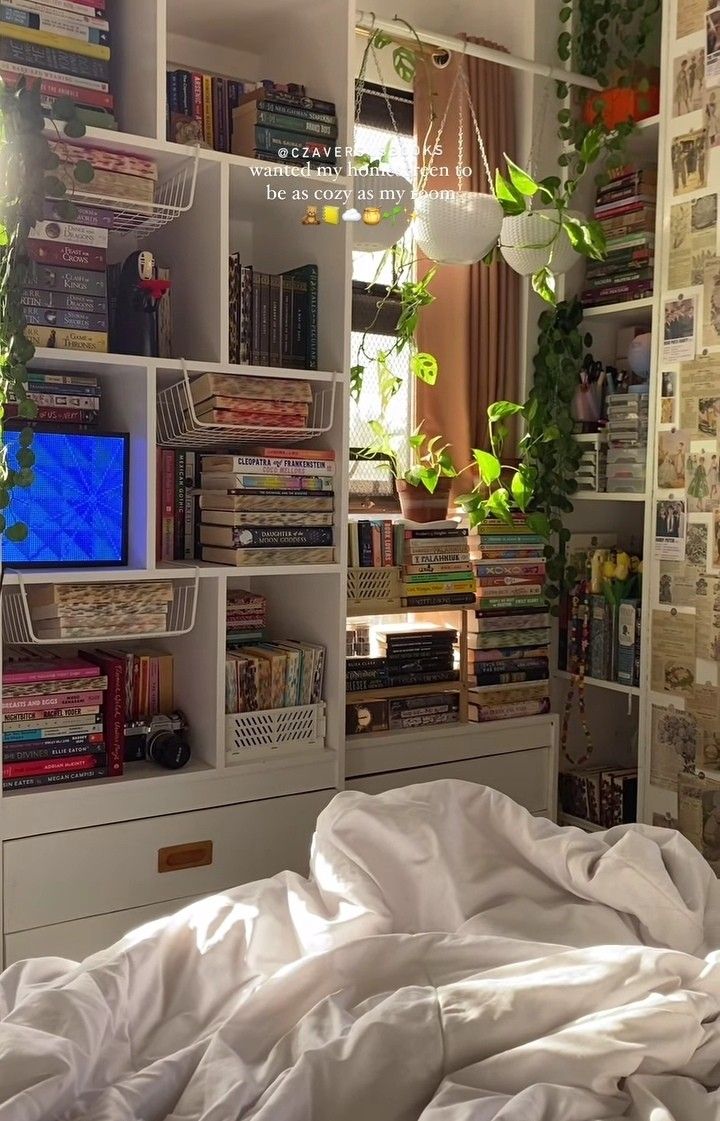 an unmade bed in front of a book shelf filled with books