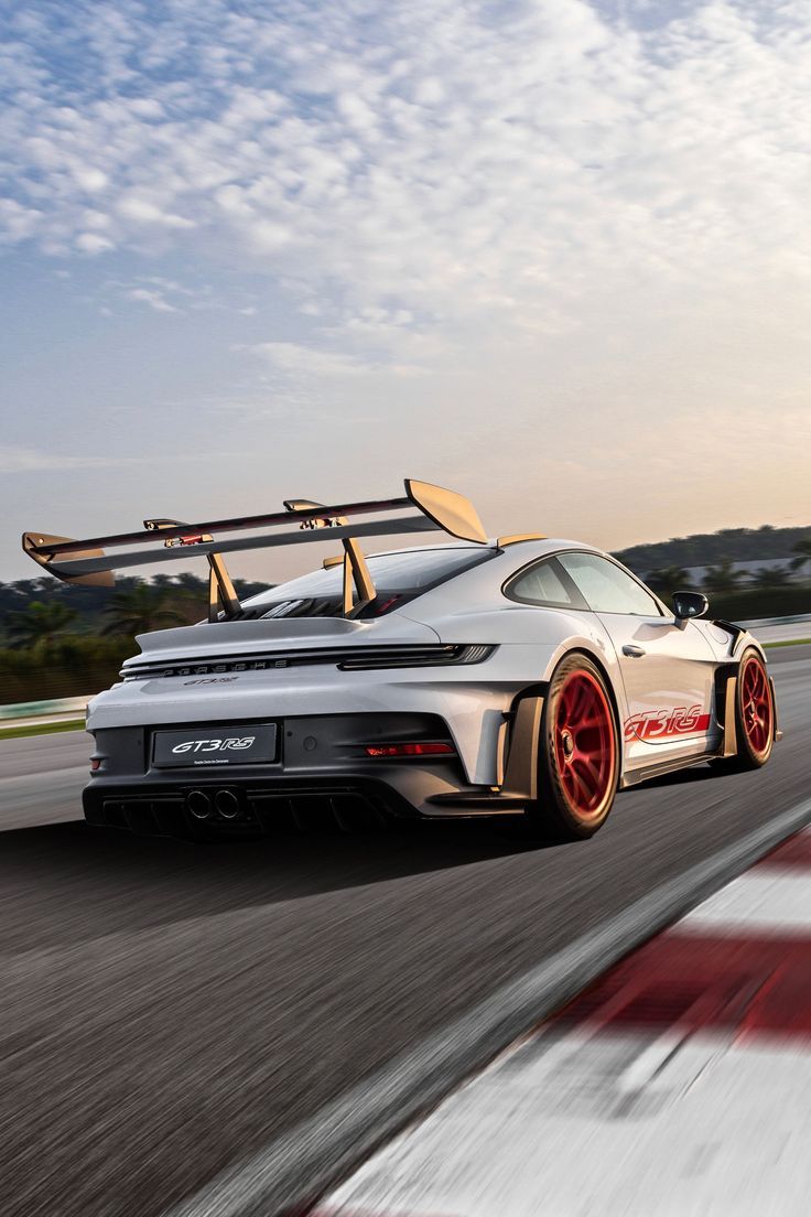 a white car driving down a race track with skis on the roof and luggage strapped to it's back