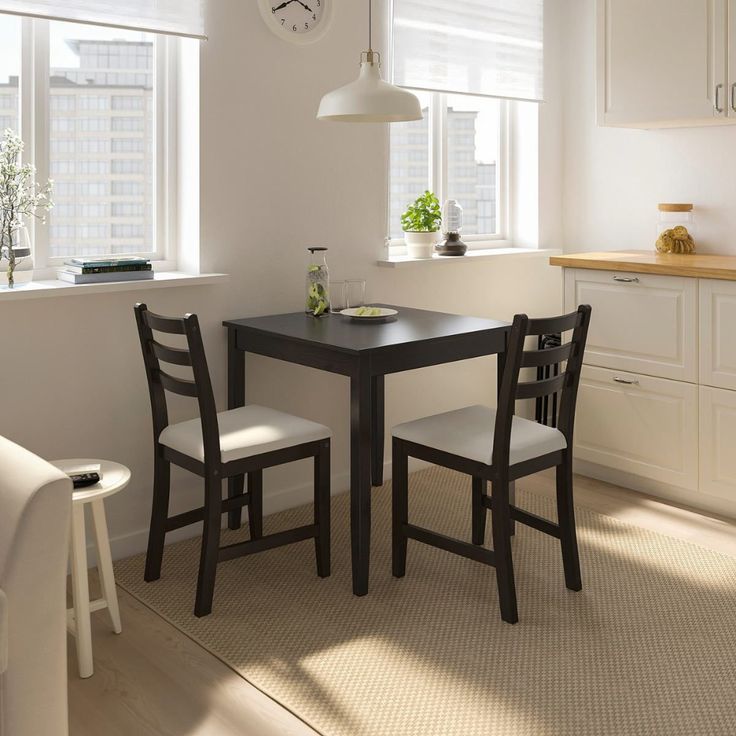 a kitchen table with two chairs and a clock on the wall