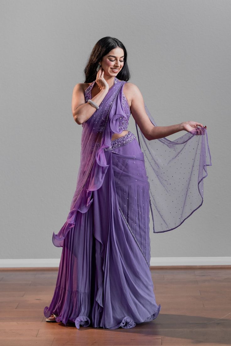 A purple lehenga ruffle saree paired with a fun halter blouse DELIVERY TIMEPlease allow 1 week for your outfit to be dispatched. FABRIC DETAILSGeorgette Professional cleaning only. Floor-length Ruffled Blouse Piece For Party, Floor-length Ruffled Dupatta For Party, Floor-length Ruffled Party Dupatta, Purple Sleeveless Wedding Set, Bollywood Style Floor-length Saree With Ruffles, Bollywood Style Floor-length Ruffled Saree, Bollywood Style Purple Pre-draped Saree For Wedding, Evening Saree Choli With Ruffles, Purple Pre-draped Saree With Cutdana For Party