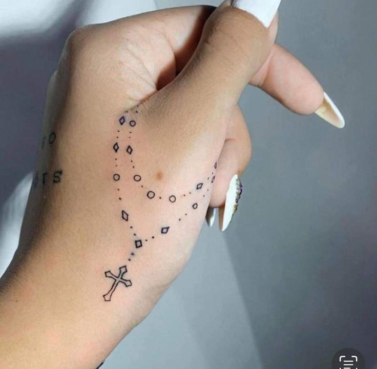 a woman's hand with a cross tattoo on it