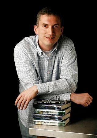 a man sitting at a table with stacks of books