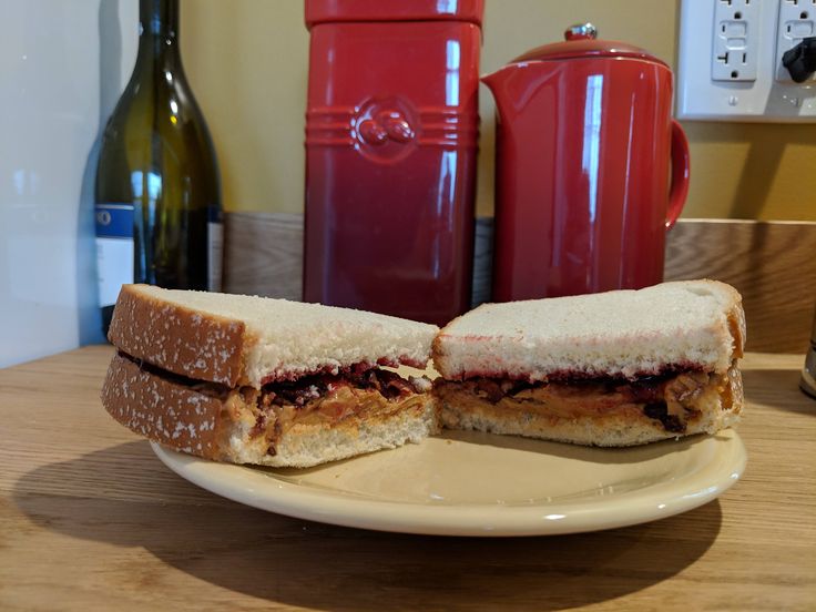 a sandwich cut in half sitting on top of a white plate next to a bottle