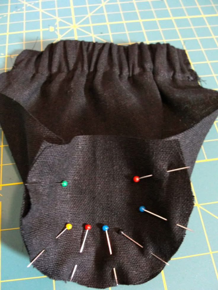 a black bag with pins sticking out of it on top of a blue cutting board