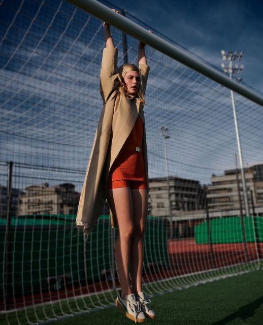 a woman standing on top of a soccer field next to a goalie net with her hands in the air