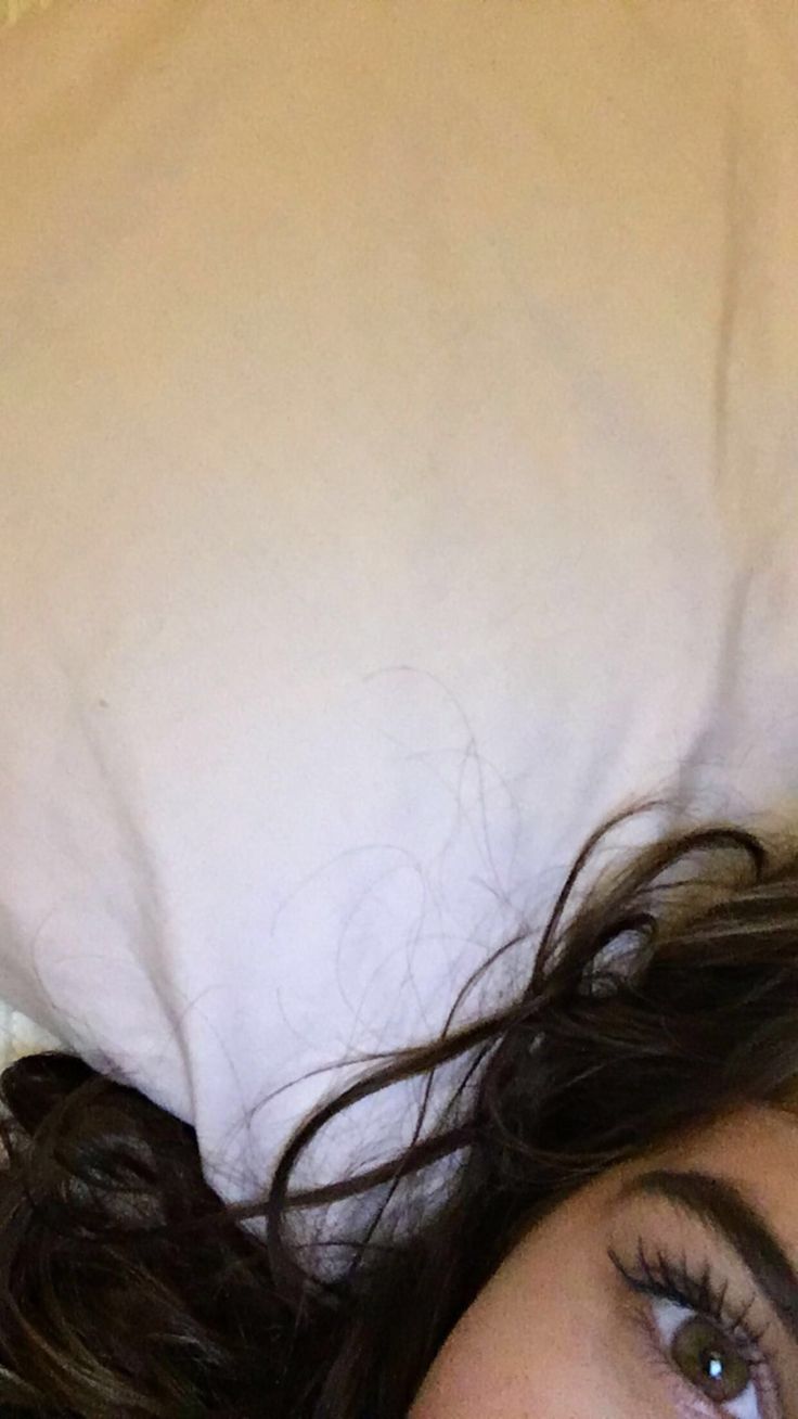 a close up of a person laying in bed with a pillow on top of their head