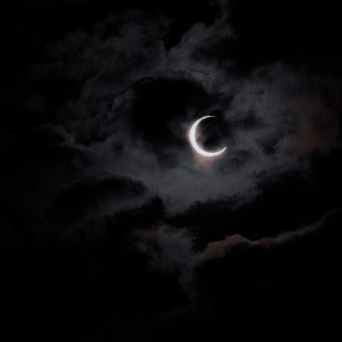 the moon is partially obscured by dark clouds