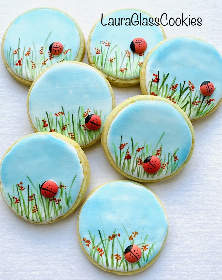 six decorated cookies with ladybugs on them sitting in the middle of some grass