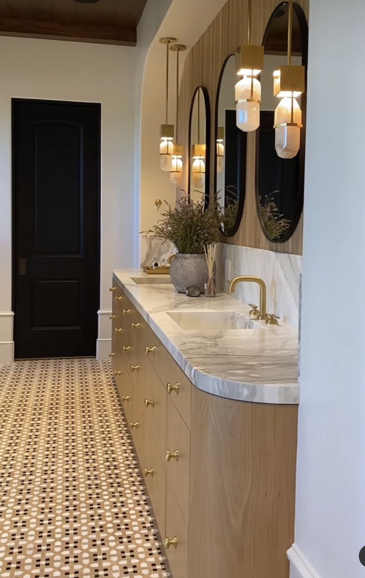 a bathroom with two sinks and mirrors on the wall next to a doorway that leads into another room