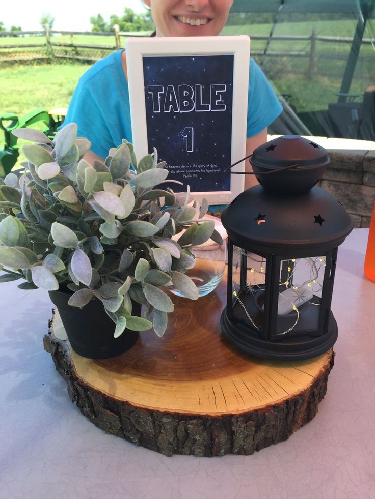 a person sitting at a table with a sign and potted plant