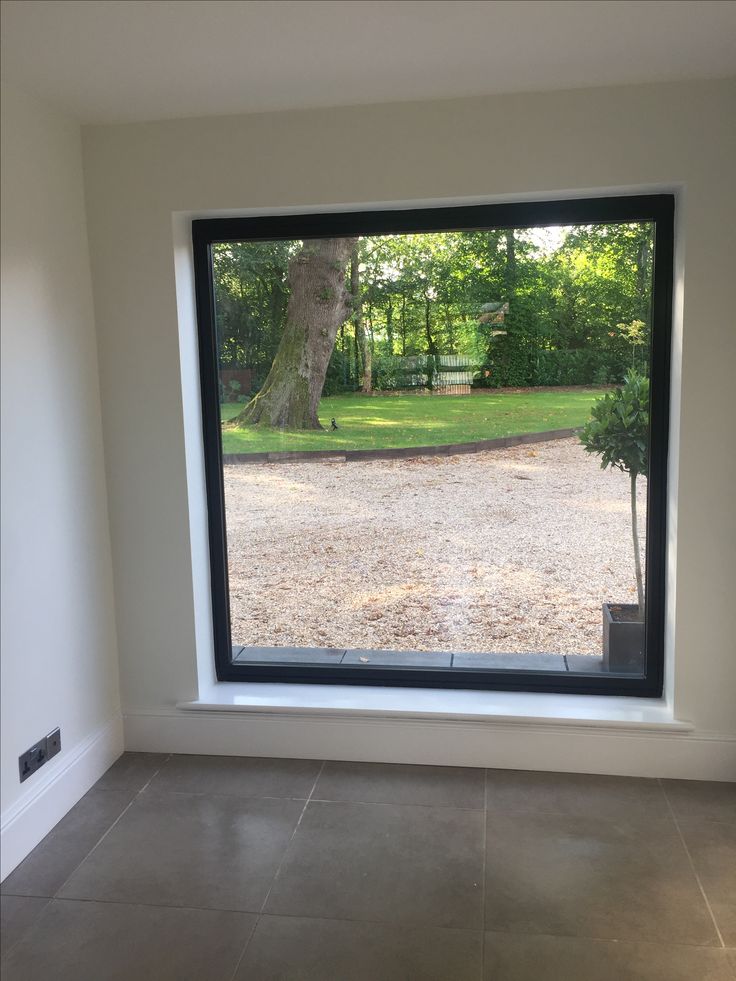 an empty room with a large window looking out at a park and a tree in the distance