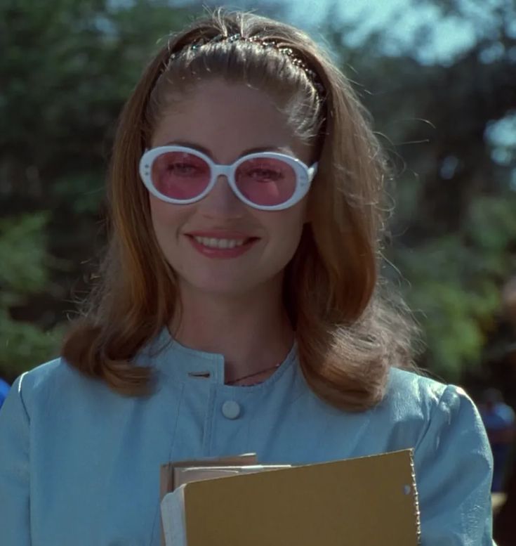 a woman wearing white sunglasses and holding a folder