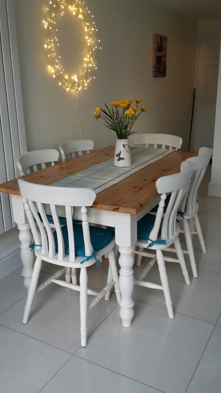 a dining room table with white chairs and lights on the wall