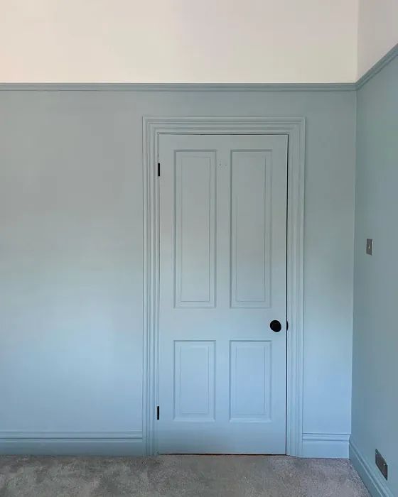 an empty room with two doors and carpeted flooring on the ground, in front of a white wall