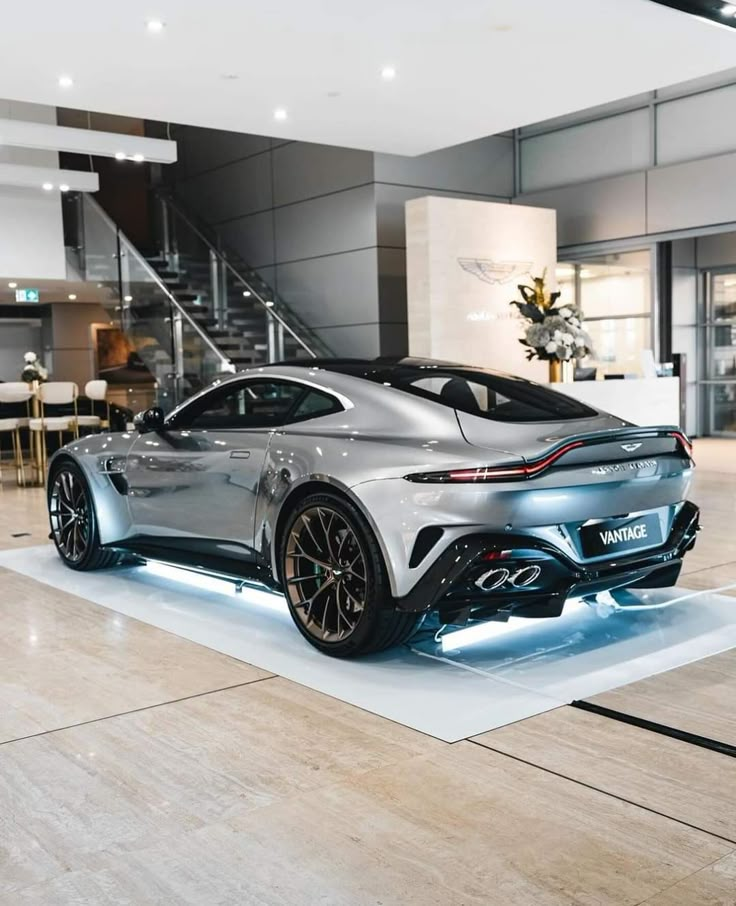 a silver sports car on display in a showroom with stairs leading up to it