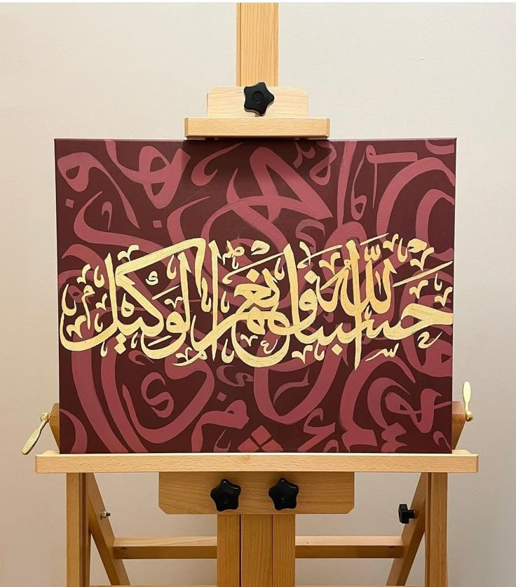 an easel with a painting on it that has arabic calligraphy written in gold