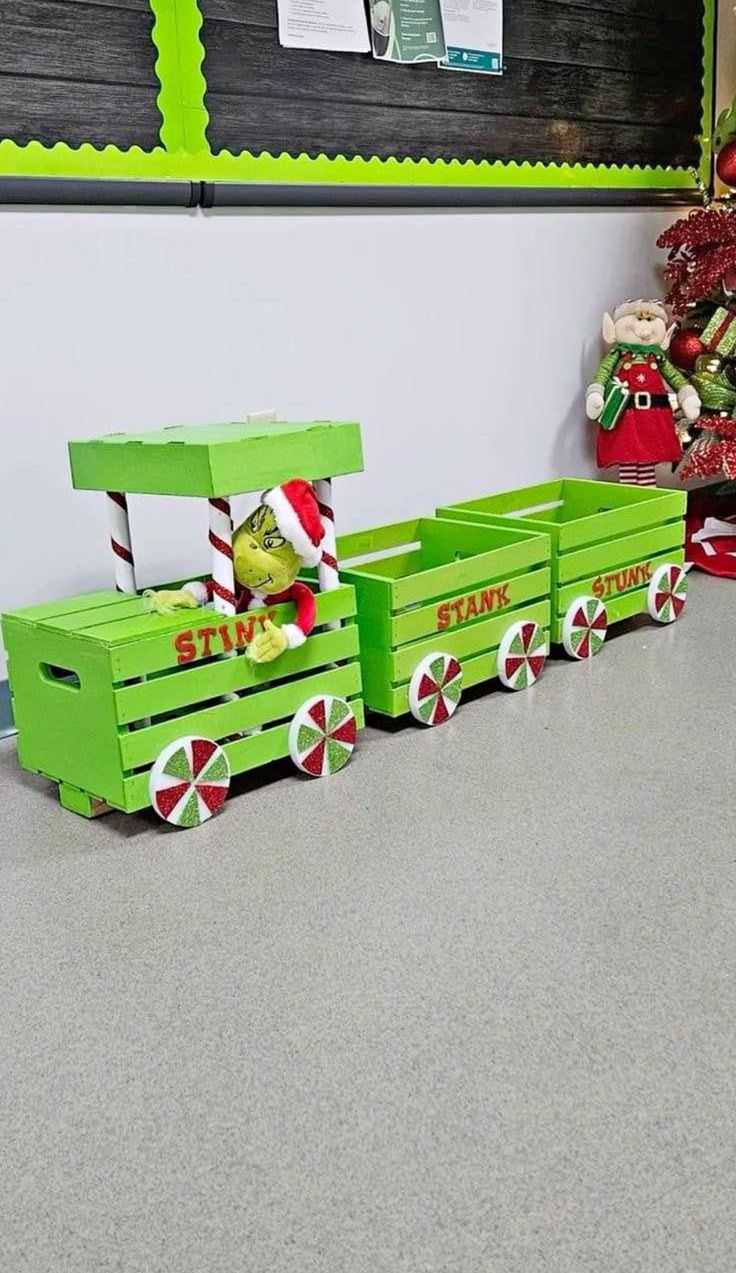 a green toy train sitting on top of a floor next to a christmas tree and other decorations