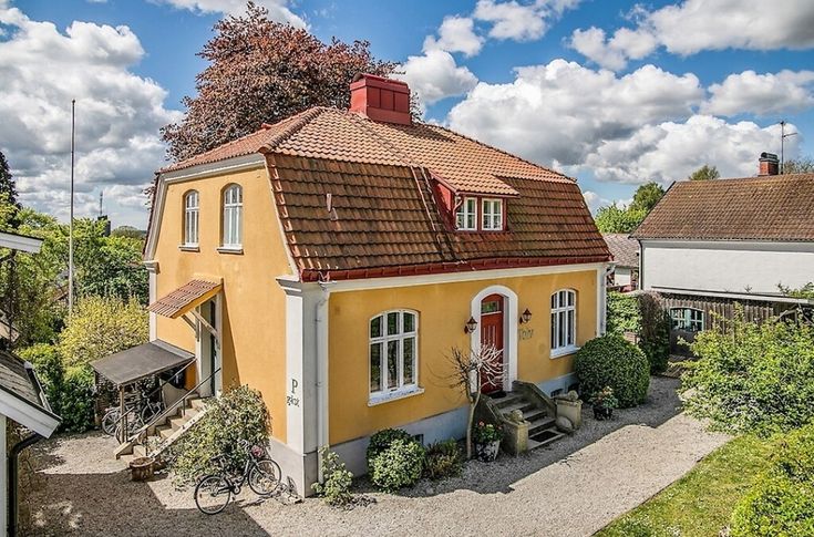 a yellow house with red roof and white windows