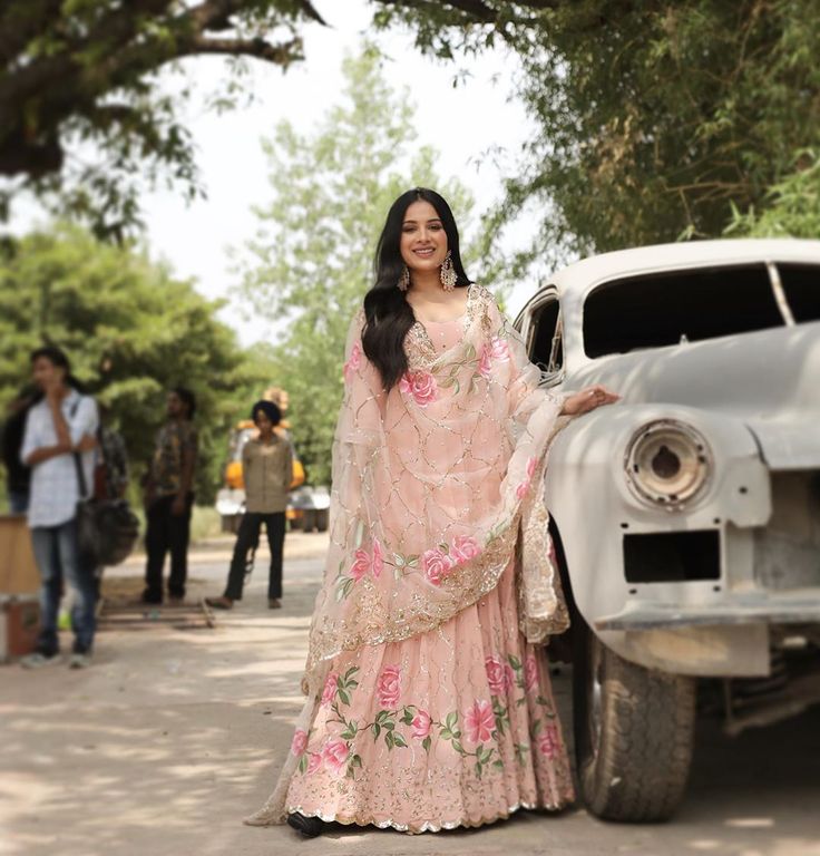 a woman standing in front of an old car